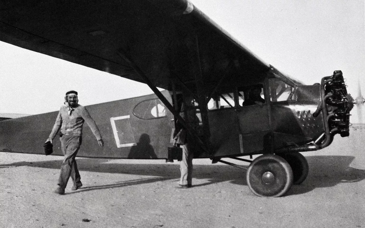 Person standing next to a Mukamalah airplane in the Saudi Arabian desert